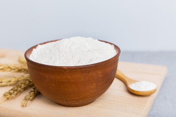 Flat lay of Wheat flour in wooden bowl with wheat spikelets on colored background. world wheat crisis