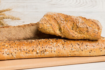 Freshly baked bread on cutting board against white wooden background. perspective view bread with copy space