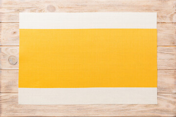 Top view of yellow tablecloth for food on wooden background. Empty space for your design.