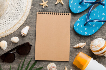 Blank writing book with summer beach accessories on background, copy space. Flat lay with copy space