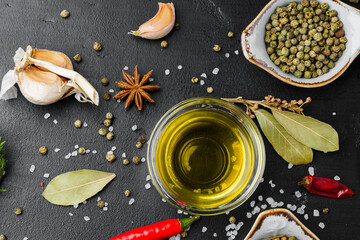 Olive oil, herbs and spices on black background