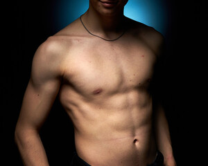 Naklejka premium a healthy athletic teenager shows off his body against a dark background, the concept of proper nutrition