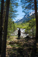 A man sits on a stone, looks into the distance, admires the mountains and the river