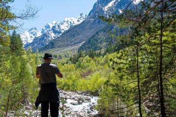 A man sits on a stone, looks into the distance, admires the mountains and the river