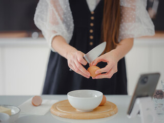 Beautiful young woman smiling while baking in kitchen at home ,decorating cake of chocolate cake,cooking class, culinary, bakery, food and people concept