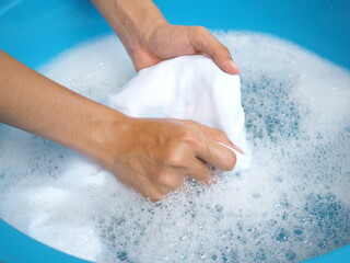 Woman washes clothes by hand in detergent water. top view photo, blurred.