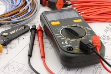 Multimeter and tools for installing an electrical control panel in close-up on an electrical diagram.