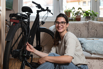 Obraz premium Young self learned woman or girl mechanic fixing and repairing her bicycle at her home. Female repair chain on rear wheel before she start to ride a bike on nice sunny weather.