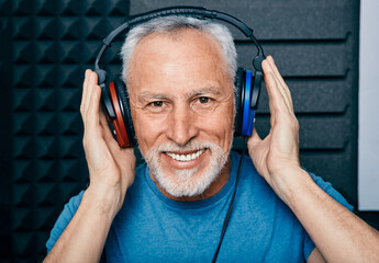 Hearing loss treatment. Positive senior man wearing audiometry headphones while hearing test and...