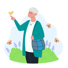 Senior woman stands in the garden and holds a bird in her hand
