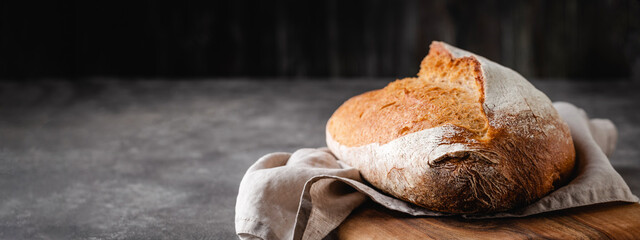 Sourdough freshly baked bread with a crispy crust on a linen napkin.