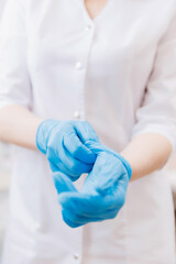 Closeup hand of woman gynecologist puts on gloves during medical in modern clinic, white background
