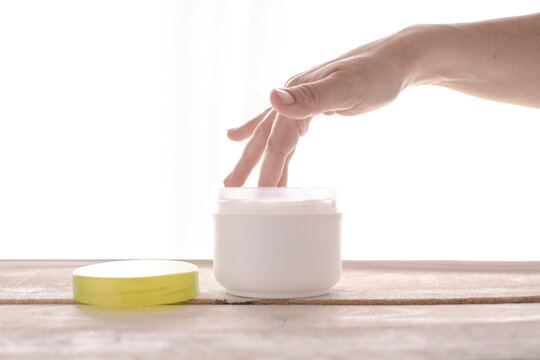 Woman applying moisturizer cosmetic on her hands. White background and empty copy space for Editor's text.