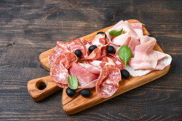 Food antipasti prosciutto ham, parma ham, salami, olives and  bread. Charcuterie plate. Two glasses of white wine or prosecco