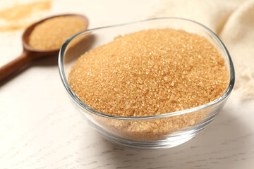 Brown sugar in bowl on white wooden table, closeup