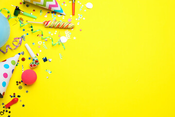 Flat lay composition with party hats and other festive items on yellow background, space for text....