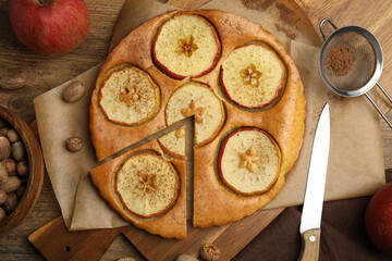 Nutmeg seeds, tasty apple pie and fresh fruits on wooden table, flat lay