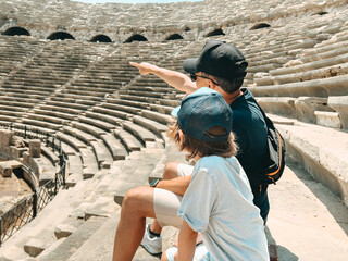 Young father dad and his school boy kid son tourists visiting ancient antique coliseum amphitheater ruins in hot summer day. - obrazy, fototapety, plakaty