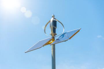 Solar panel and wind propeller mounted on a pole in the city for local power generation.
