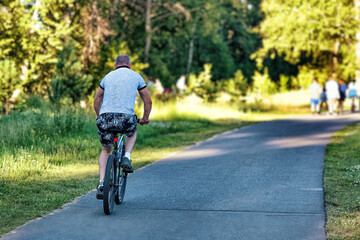 A man riding a bicycle in a park in summer in the sunny morning.