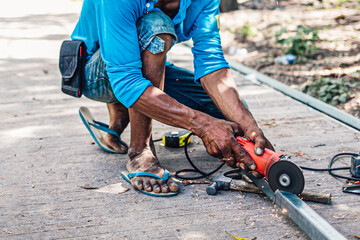 Cutting iron with steel cutter machine by Asian mechanic man at the construction site.