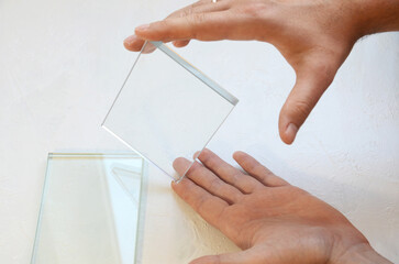 male hand holding glass sample, transparent glass in hand on white background, industrial glass