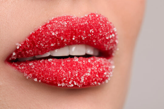 Young woman with beautiful lips covered in sugar, on light background, closeup