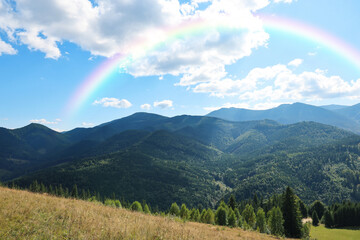 Picturesque mountain landscape and beautiful rainbow in sky