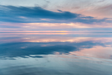 Beautiful landscape of salt lake at sunset. Blue sky with clouds are reflected in the mirror water...