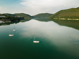 Mountain lake with turquoise water and yachts. Abrau lake in Abrau-Durso village, Russia. Mountains are reflected in the calm water. Summer nature landscape
