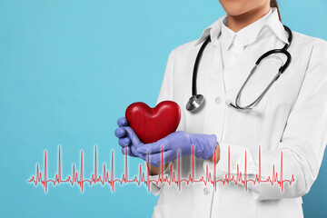 Closeup view of doctor with stethoscope holding red heart and illustration of cardiogram on...