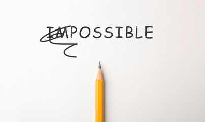 Word IMPOSSIBLE with crossed out letters IM and pencil on white background, top view. Motivation...