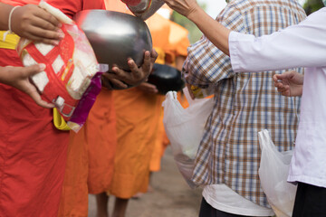 Young Buddhist monks or novice monk are given food, drinking water,banknotes offerings from people.