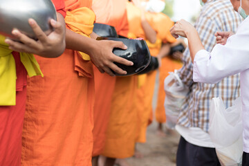 Young Buddhist monks or novice monk are given food, drinking water,banknotes offerings from people.