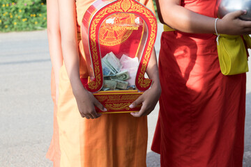 Young Buddhist monks or novice monk are given food, drinking water,banknotes offerings from people.
