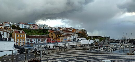 Rainy day with a rainbow in a small town with orange roofs in the Azores