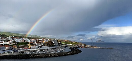 Rainy day with a rainbow in a small town with orange roofs in the Azores