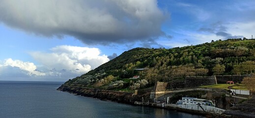 Rainy day with a rainbow in a small town with orange roofs in the Azores