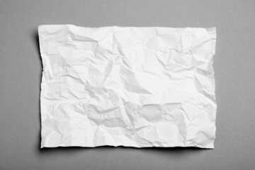 Obraz premium Sheet of white crumpled paper on grey background, top view