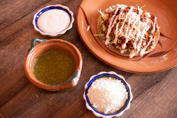 Tostada de tinga de pollo con crema, queso y salsa 