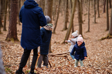 Kids wear jacket and hat in early spring forest.