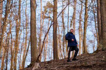 Obraz premium Young boy wear jacket and hat in early spring forest.