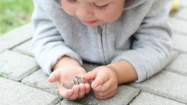 curious child boy exploring playing wild snail animal, holding palm, touching it, watching snail crawling. baby boy kid smiling enjoying snail. caucasian toddler boy meeting garden snail outdoors 