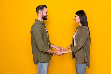Profile side photo of young lovely couple spouses hold hands romance isolated over yellow color background