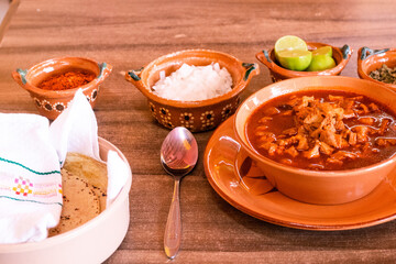 Menudo con tortillas, cebolla, chile quebrado y limones 