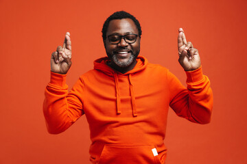 Adult happy african american man keeping fingers crossed