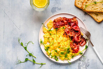 Traditional breakfast scrambled eggs with fried bacon