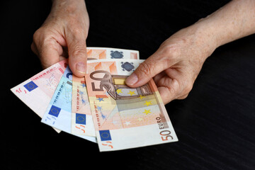 Elderly woman with euro notes in wrinkled hands. Concept of pension payments, savings at...