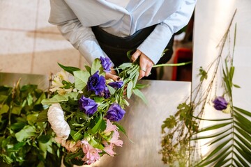White young woman making bouquet with fresh flowers in florist shop