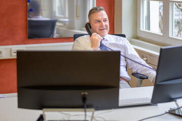 Thoughtful businessman taking a phone call in office